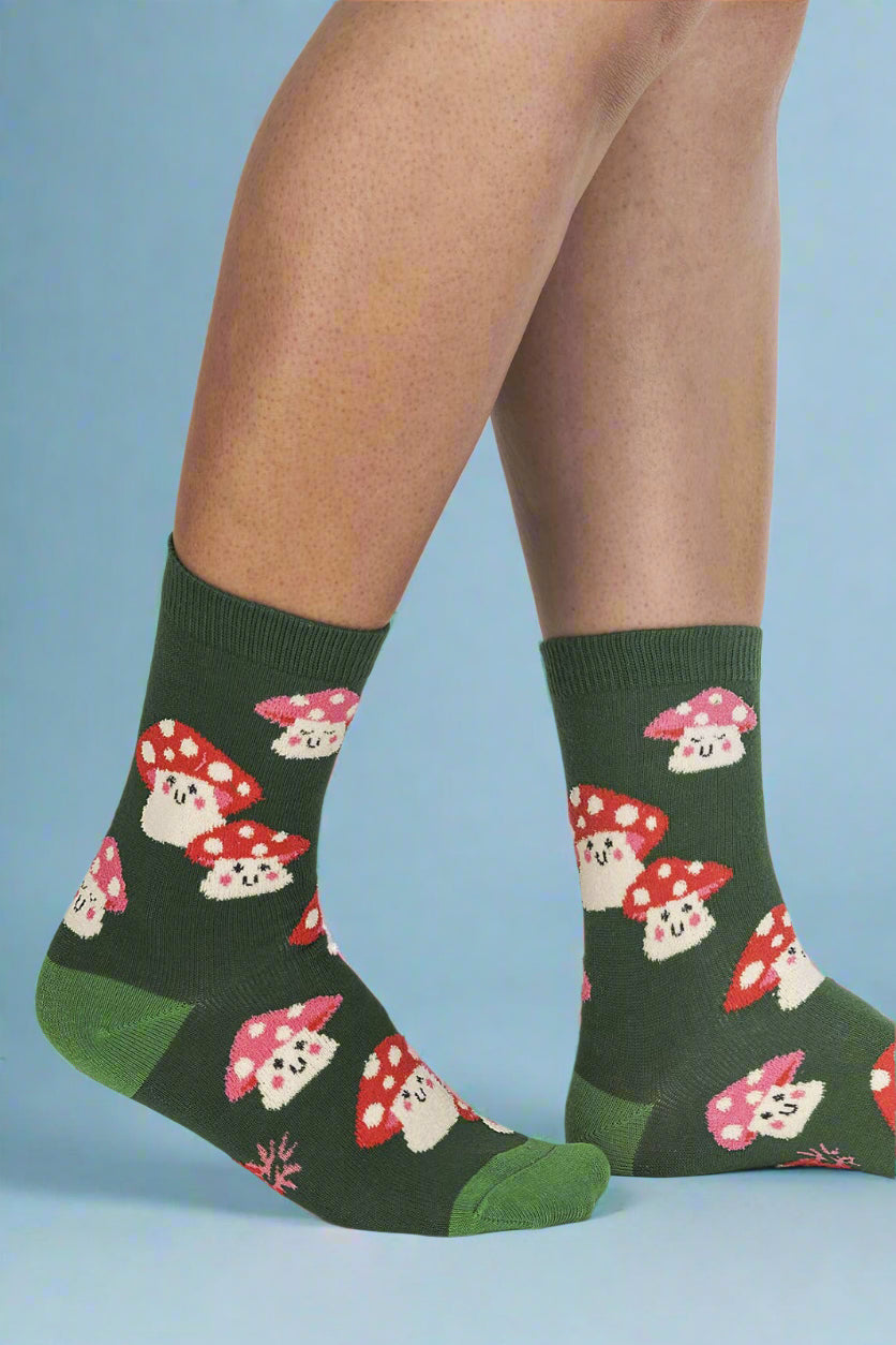 Green socks with mushroom pattern worn by a person on a white background