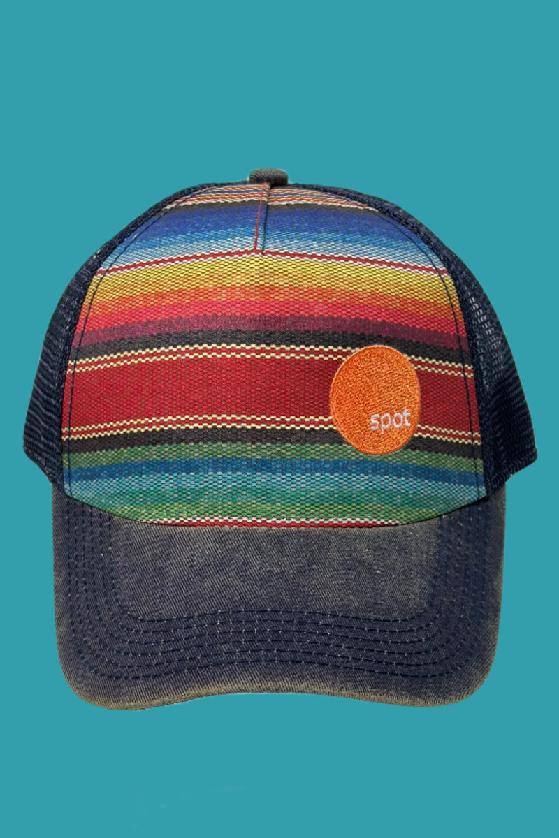 Mesh back trucker style hat featuring a distressed denim brim and a colorful striped pattern with an embroidered Spot logo.
