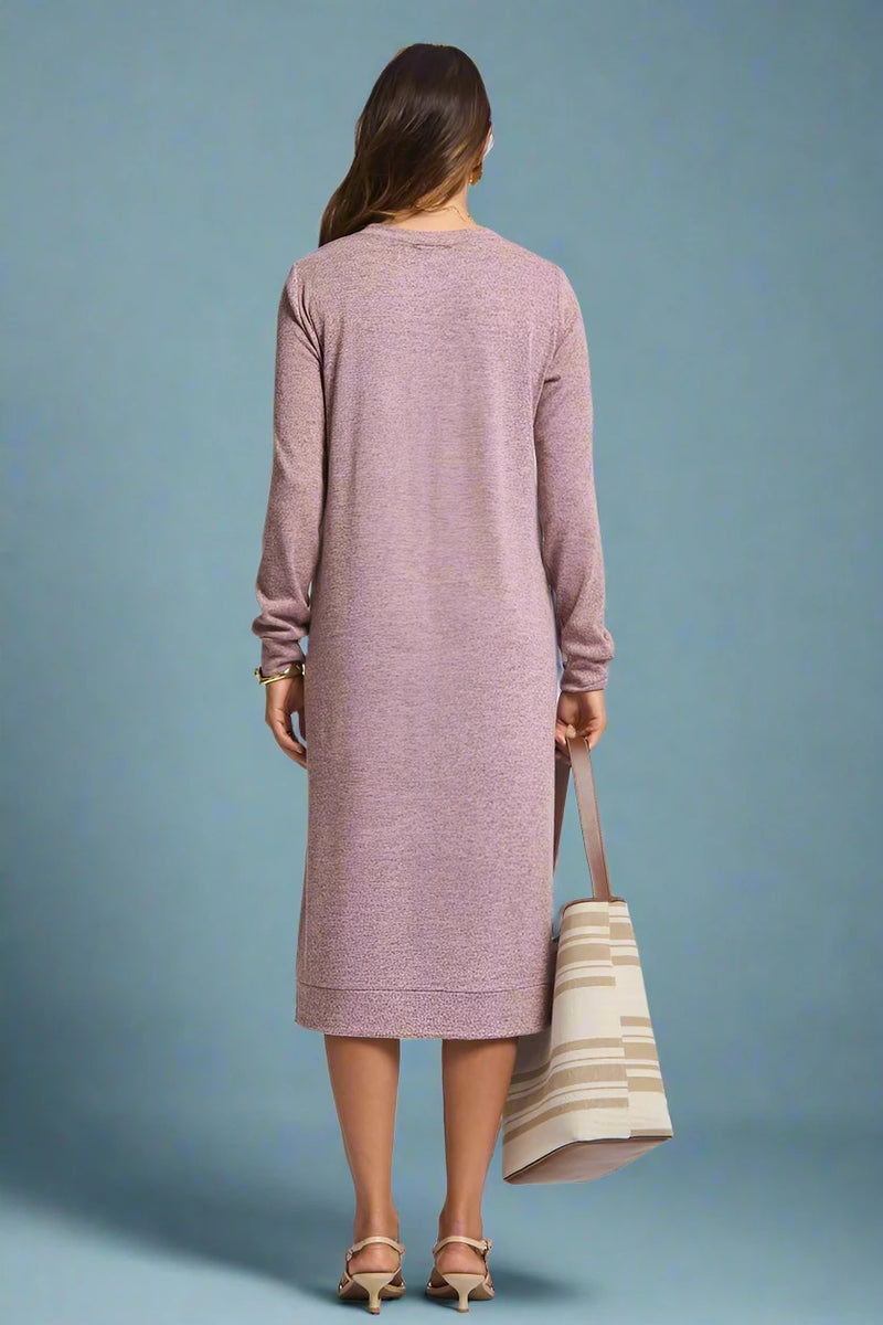 Woman wearing a long pink dress holding a striped bag on a plain background