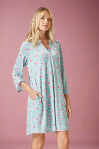 Woman wearing a patterned long sleeve dress on a plain background