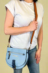 Model is carrying a blue color block cross body bag. 