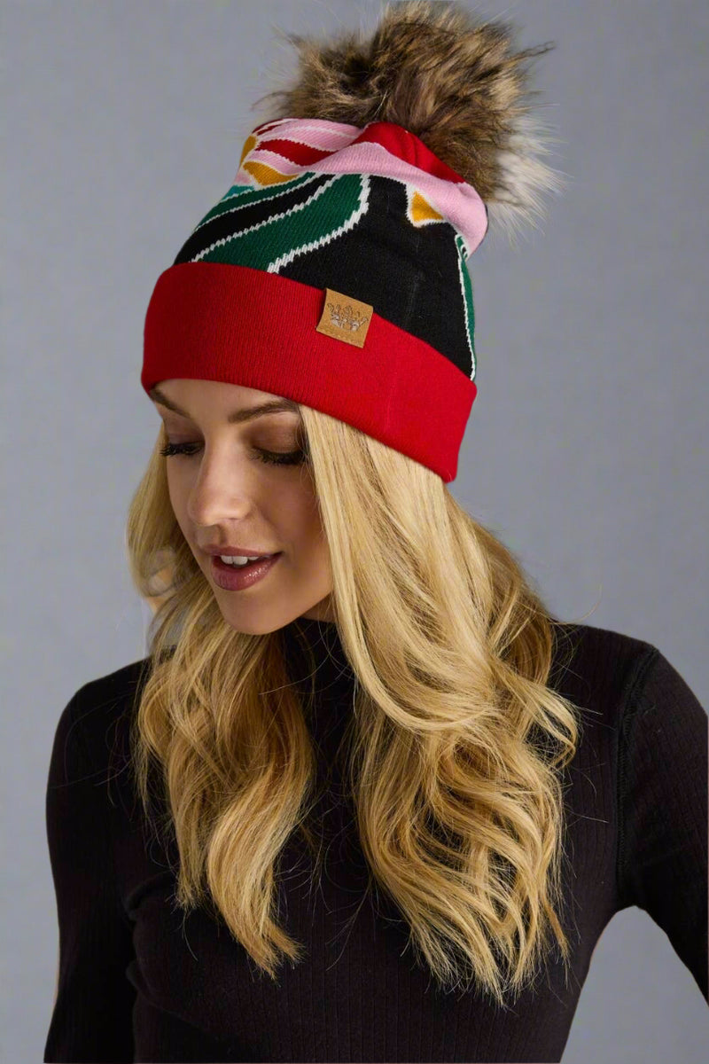 Woman wearing a colorful beanie with a pom-pom on a gray background