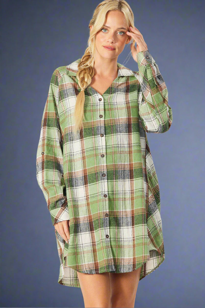 Model is wearing an olive plaid button down shirt dress. It features a v neck and long sleeves which can be rolled. 