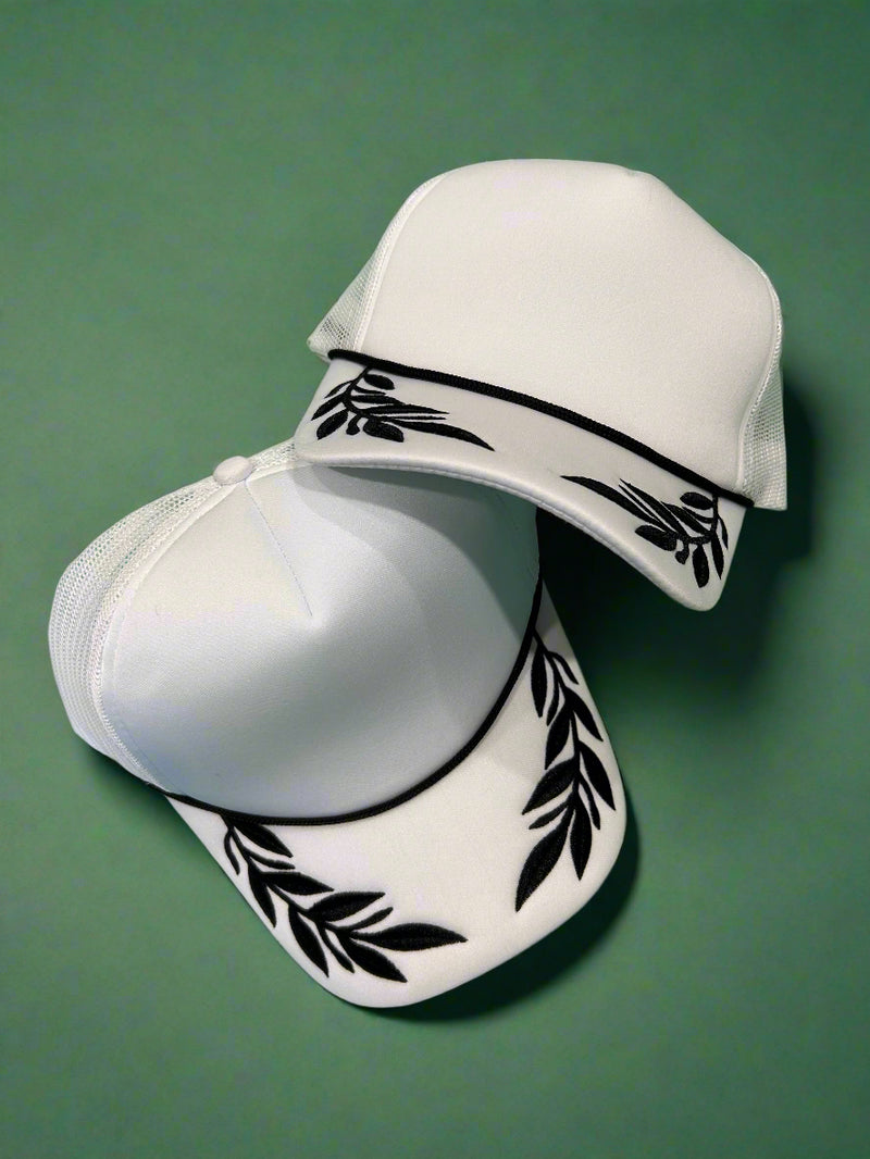 White foam trucker hat with black leaf pattern. Adjustable.
