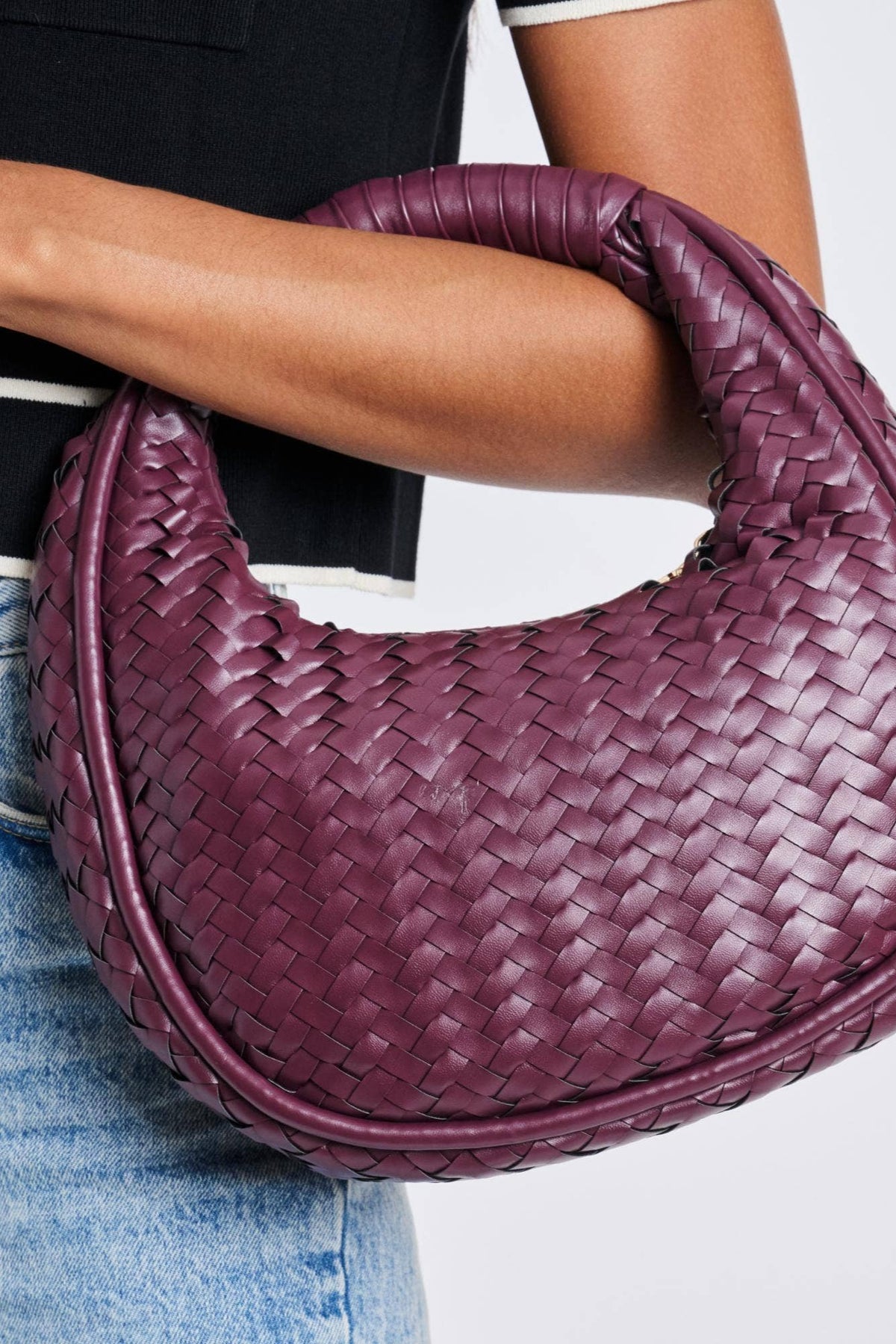 Model is carrying a woven purple bag with zipper closure. 
