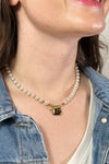 Model is wear a short pearl necklace with gold heart charm. 