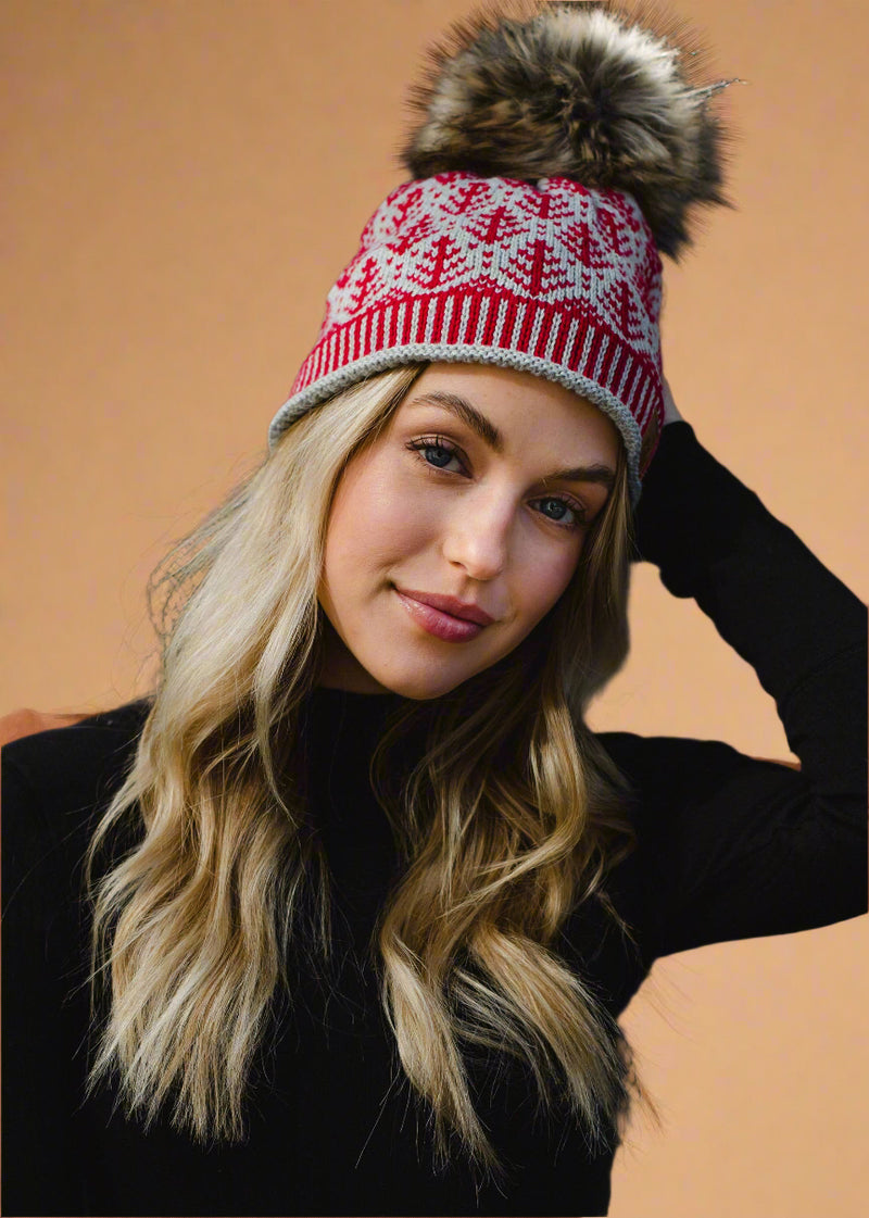 Woman wearing a red and white patterned beanie with a fur pom-pom against a dark background