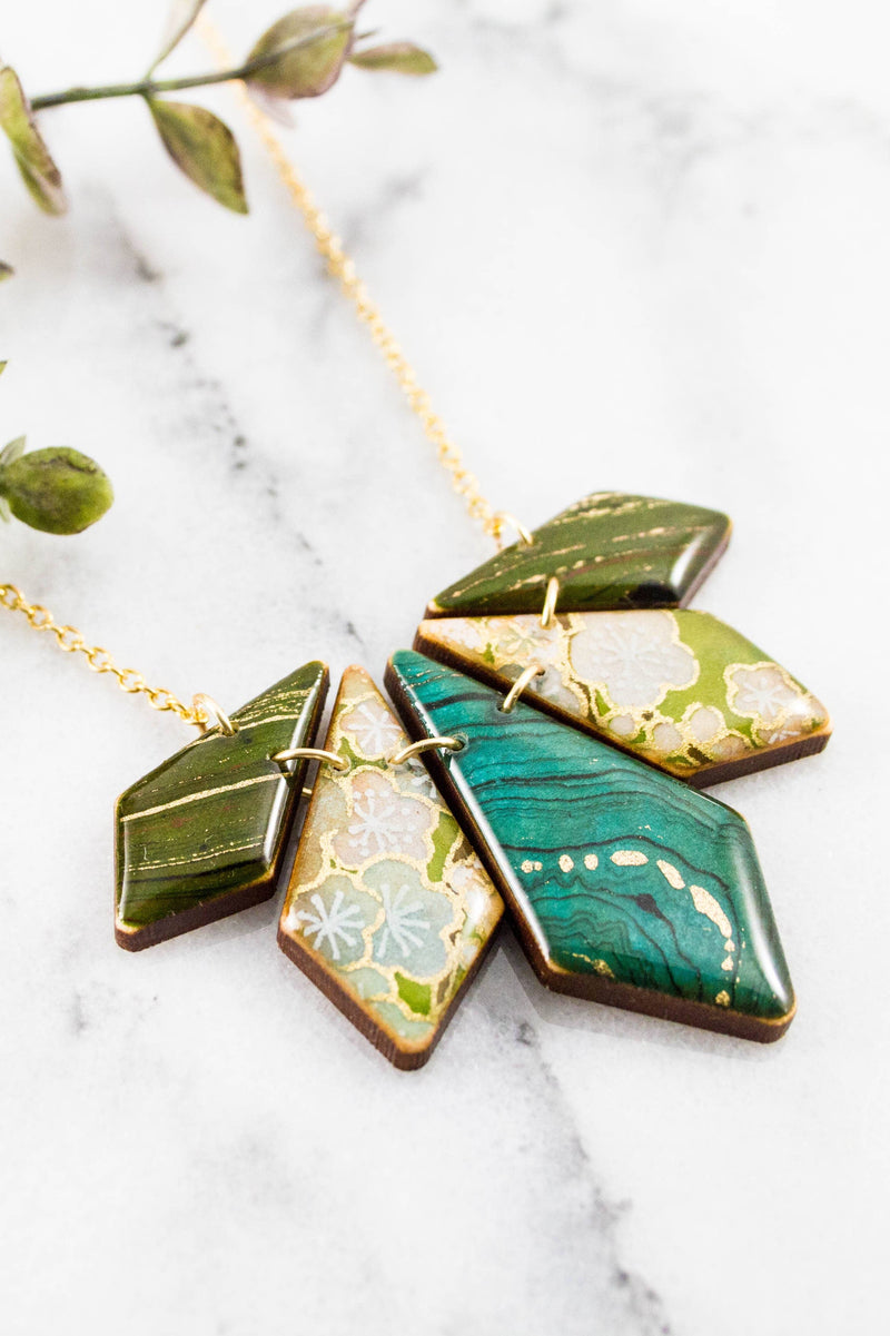 This handcrafted, geometric necklace with gold, turquoise, olive, lime, brown, and cream hues is crafted from sustainably harvested North American hardwood and vintage Japanese yuzen papers.
