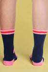 Navy socks with pink accents worn by a person on a light gray background