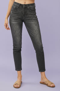 Person wearing black distressed jeans on a plain background