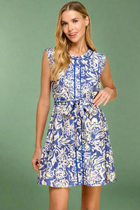 Woman wearing a blue and white floral dress on a beige background.