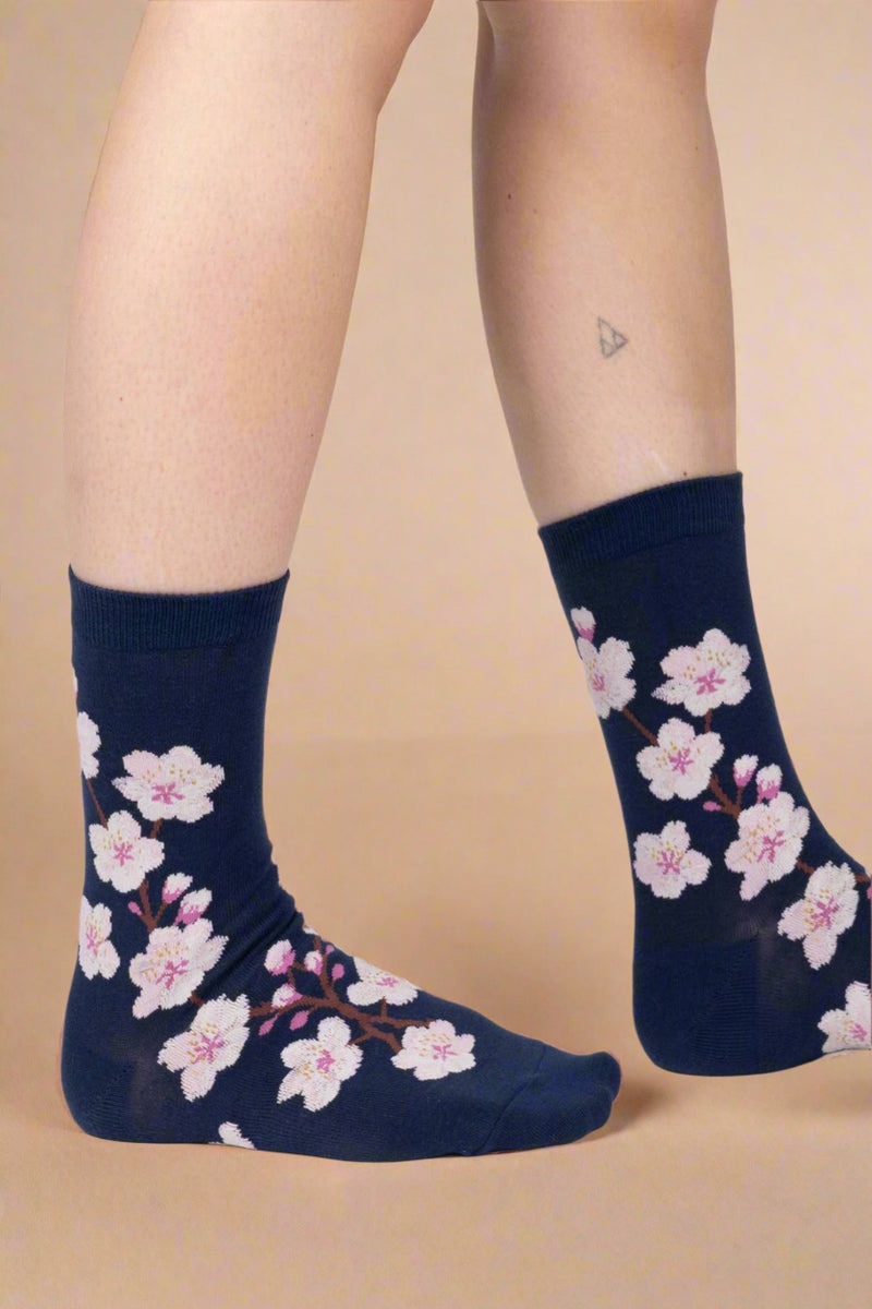 Navy socks with pink floral pattern worn by a person on a white background