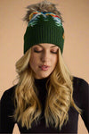 Woman wearing a green knit beanie with colorful pom-pom against a gray background