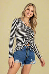 Model is wearing a black and white striped long sleeve top with ruched front and halter neck line. 