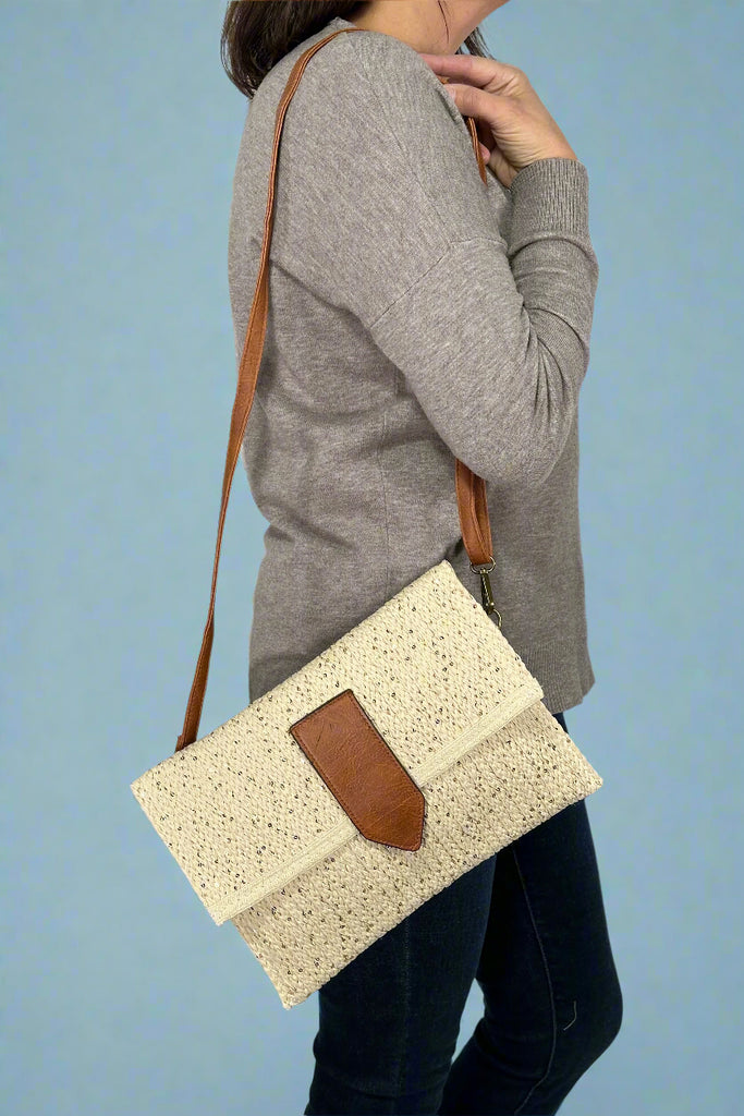 Model is wearing a metallic straw crossbody that can convert to a clutch.