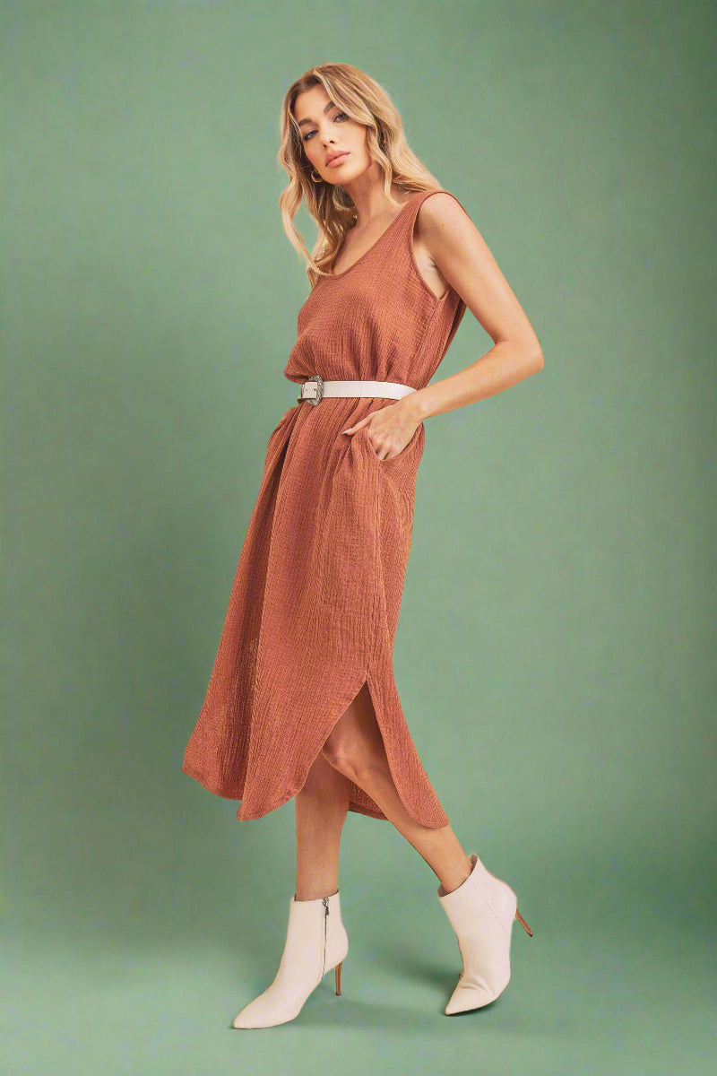 Woman wearing a rust-colored dress with white boots on a beige background