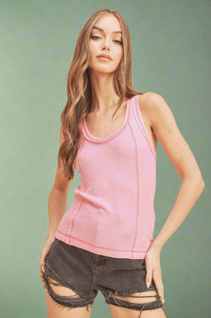 Woman wearing a pink tank top and black shorts against a beige background