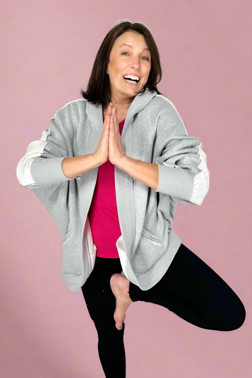 Model is wearing a heather grey, open front hooded cardigan. It is long sleeved, medium weight, and pockets.