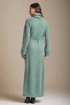 Woman wearing a long green dress on a plain background