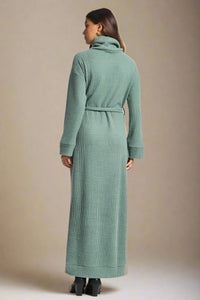 Woman wearing a long green dress on a plain background
