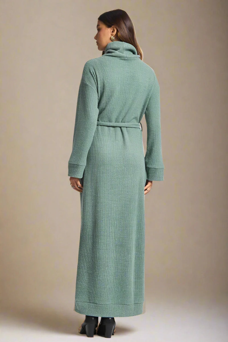 Woman wearing a long green dress on a plain background