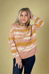 Model wearing a wave printed crew neck sweater that is light pink, mustard yellow, and white. 
