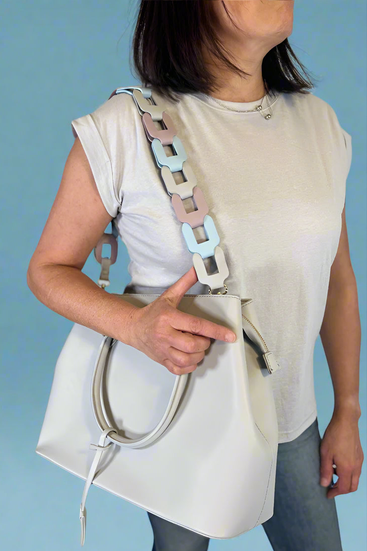 Model is carrying a large satchel with removable colorful woven strap. 