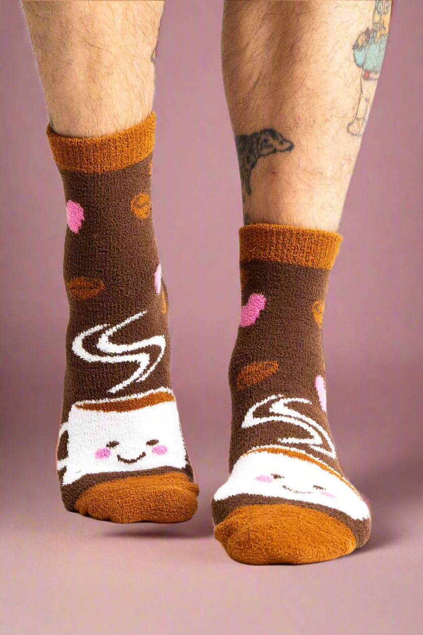 Brown socks with cartoon coffee cups and hearts worn by a person on a white background