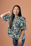 Woman wearing a floral blouse and jeans on a plain background