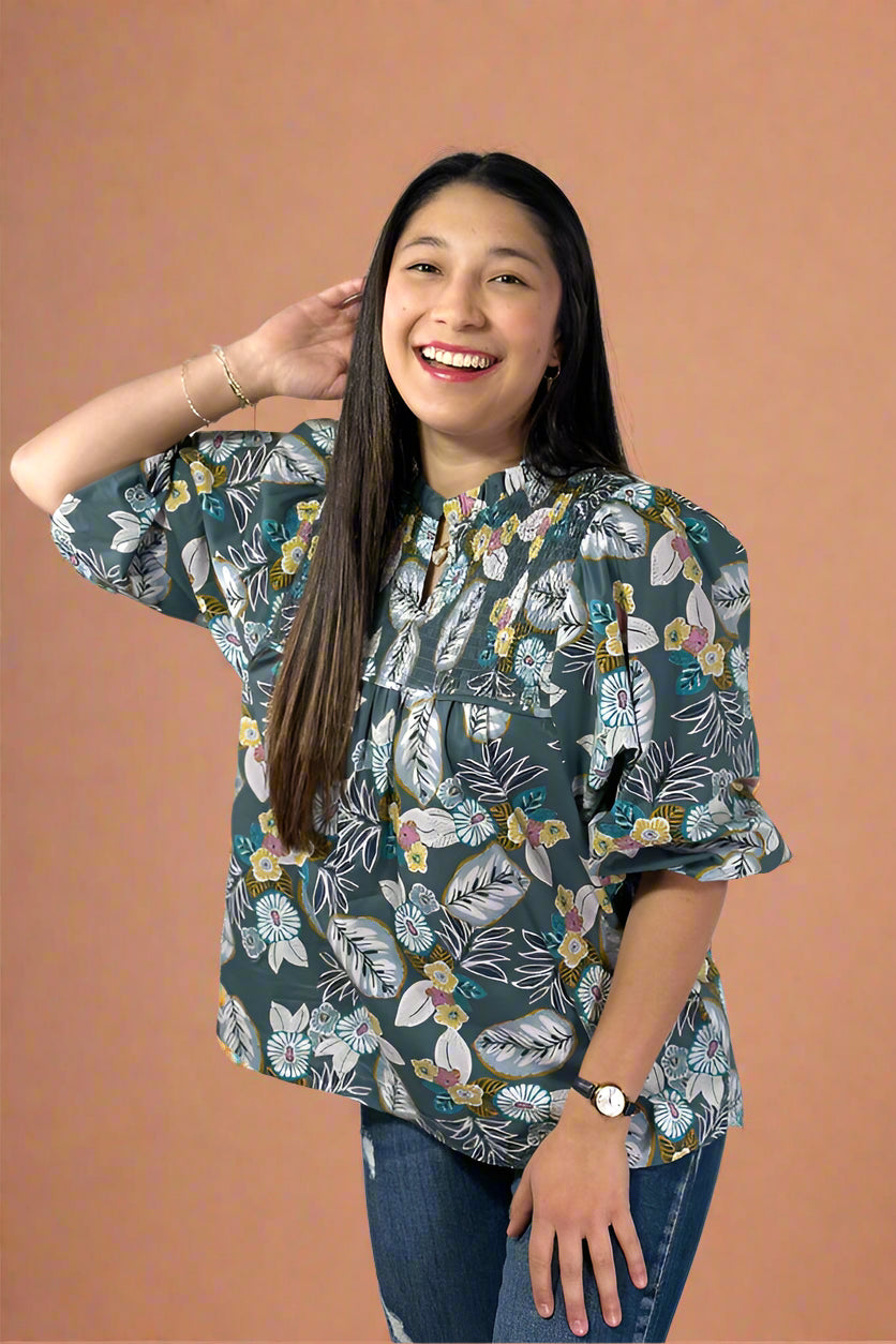 Woman wearing a floral blouse and jeans on a plain background