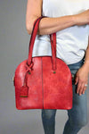 Model is carrying a large red bowler bag. 