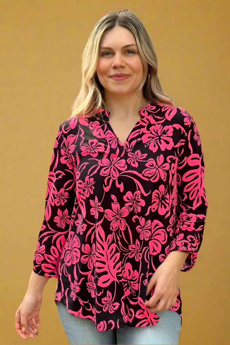 A womens lightweight, loose fit top with split v-neckline featuring a slight high-low hem, 3/4 sleeve length, and brightly colored floral print in hot pink over a black base.