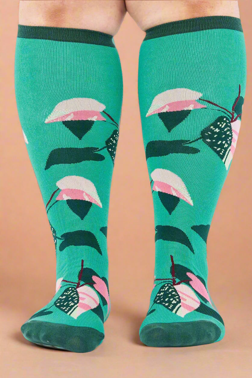 Green knee-high socks with pink and black patterns on a white background