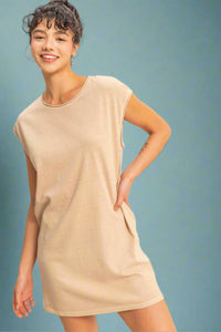 Woman wearing a beige sleeveless t-shirt dress with pockets.