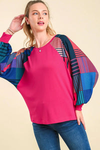 Woman wearing a pink top and colorful cardigan on a beige background