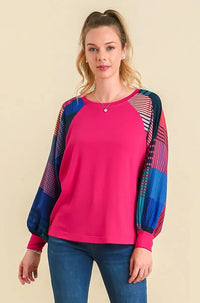 Woman wearing a bright pink top with blue and red patterned sleeves on a beige background