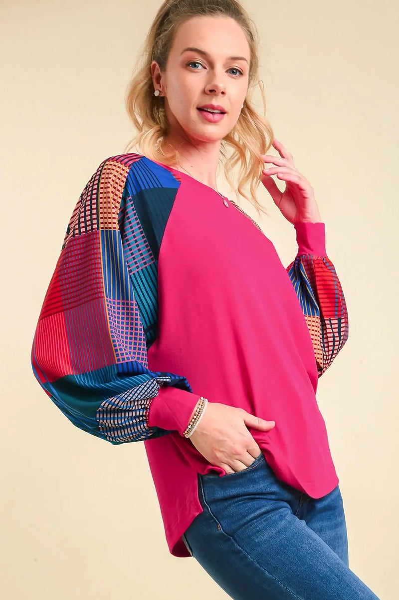 Woman wearing a pink top with colorful sleeves on a beige background