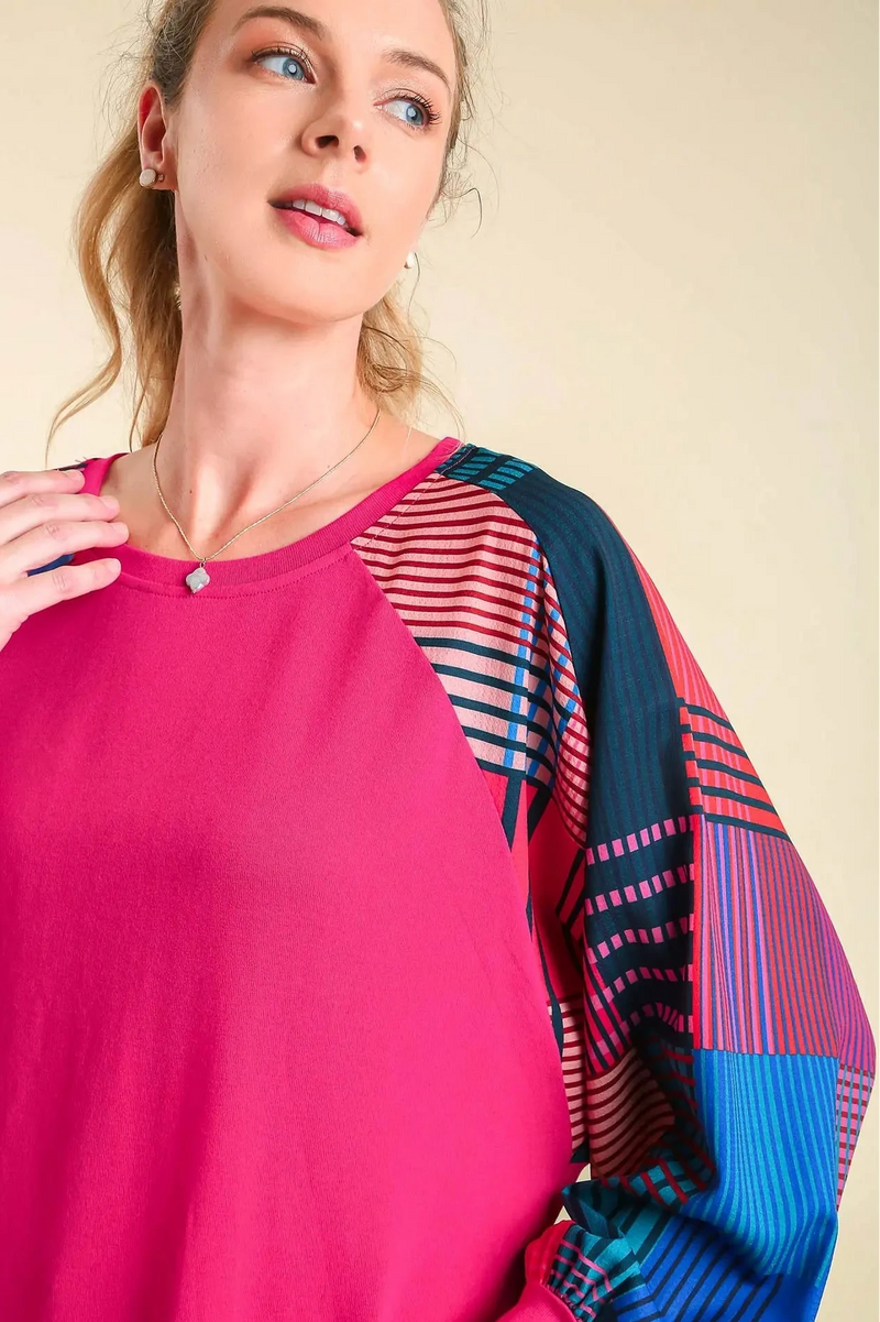 Woman wearing a pink top with colorful sleeves against a beige background