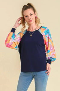 Woman wearing a colorful top and blue jeans on a beige background