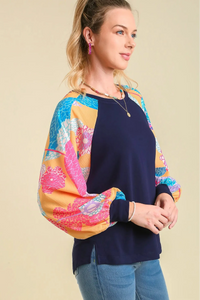 Woman wearing a navy sweater with colorful sleeves on a beige background