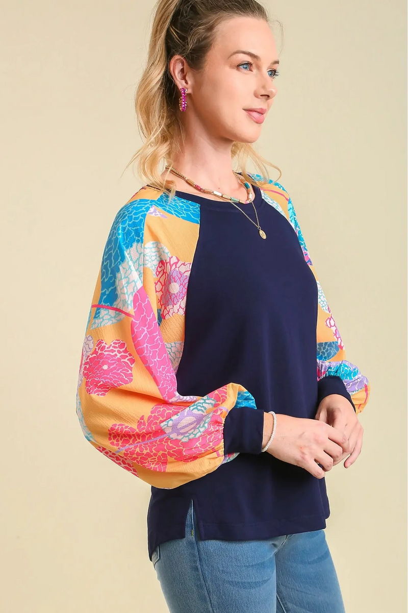 Woman wearing a navy sweater with colorful sleeves on a beige background