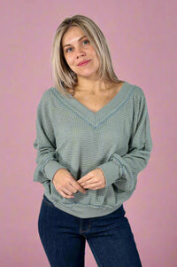 Model is wearing an oversized sage colored waffle knit v-neck top.