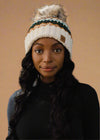 Woman wearing a patterned beanie with a pom-pom against a black background