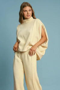 Woman wearing a cream-colored outfit against a brown background