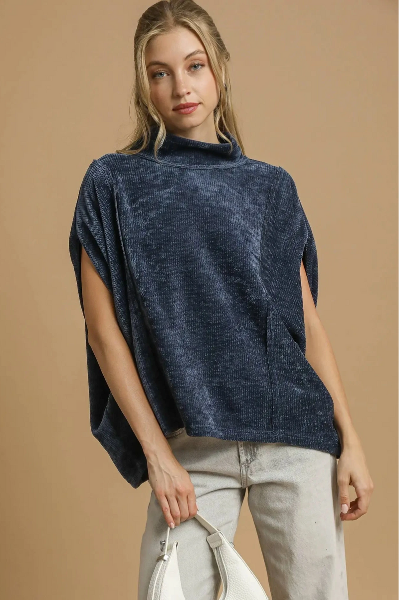 Woman wearing a navy blue poncho over a beige outfit on a beige background