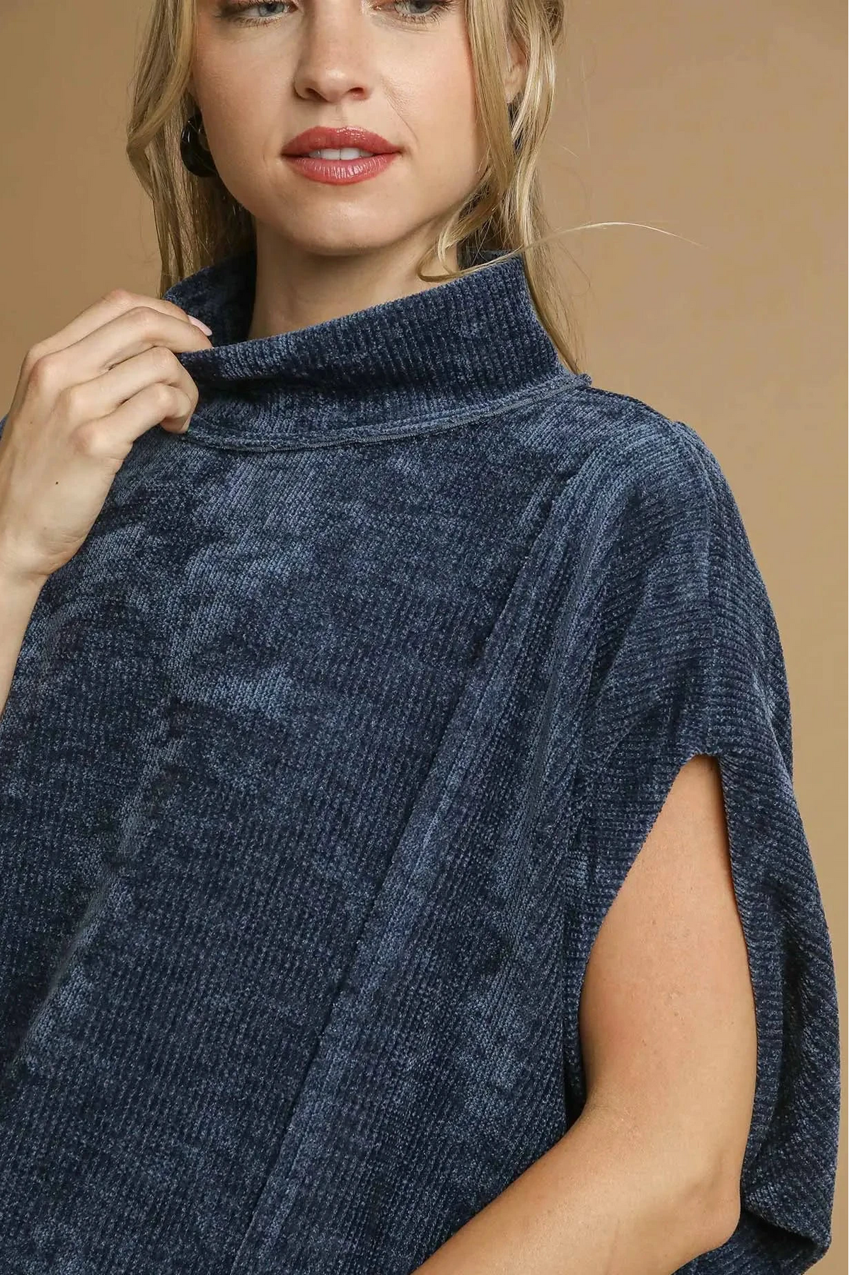 Woman wearing a navy blue poncho against a beige background