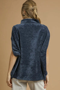 Person wearing a navy blue textured shirt against a beige background