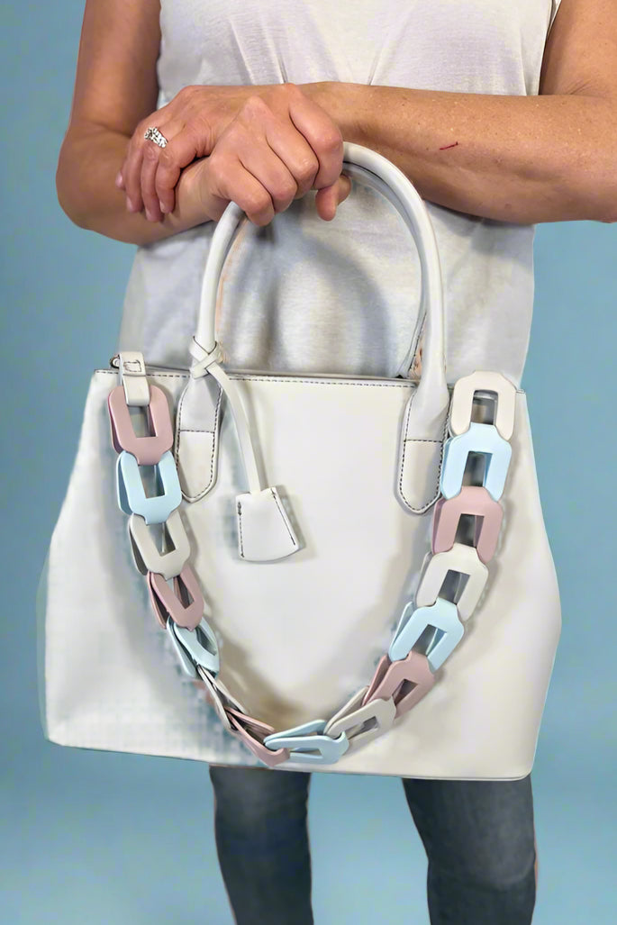 Model is carrying a large satchel with removable colorful woven strap. 