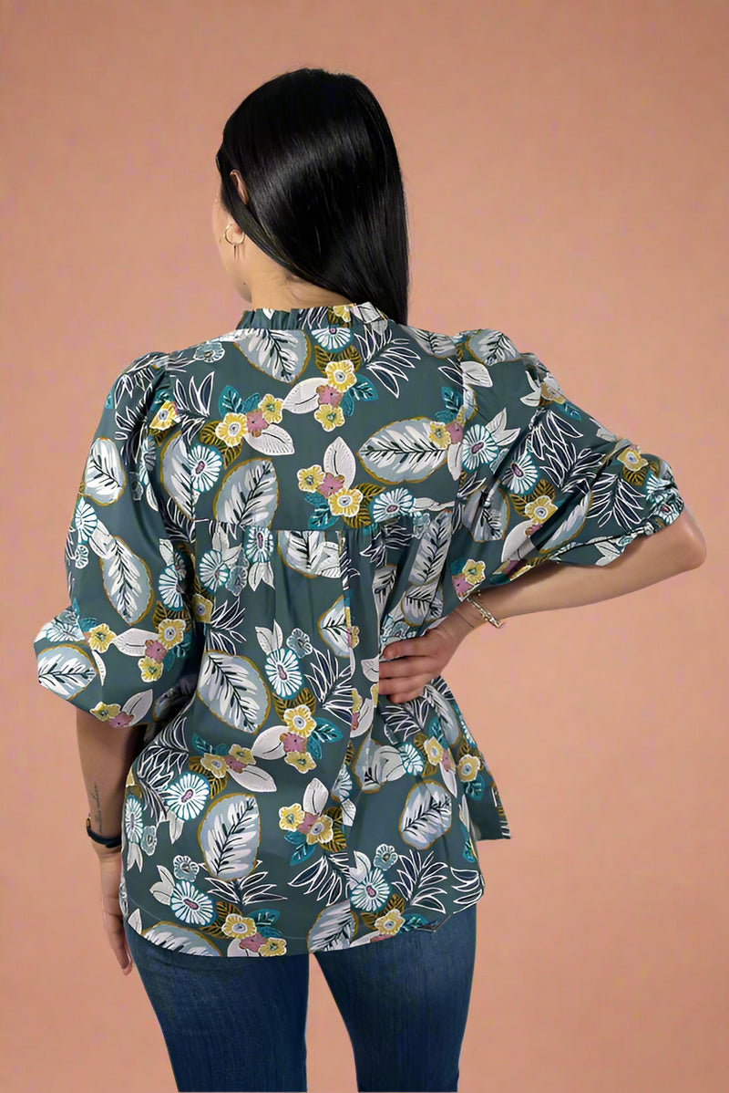 Woman wearing a floral patterned shirt against a plain background.