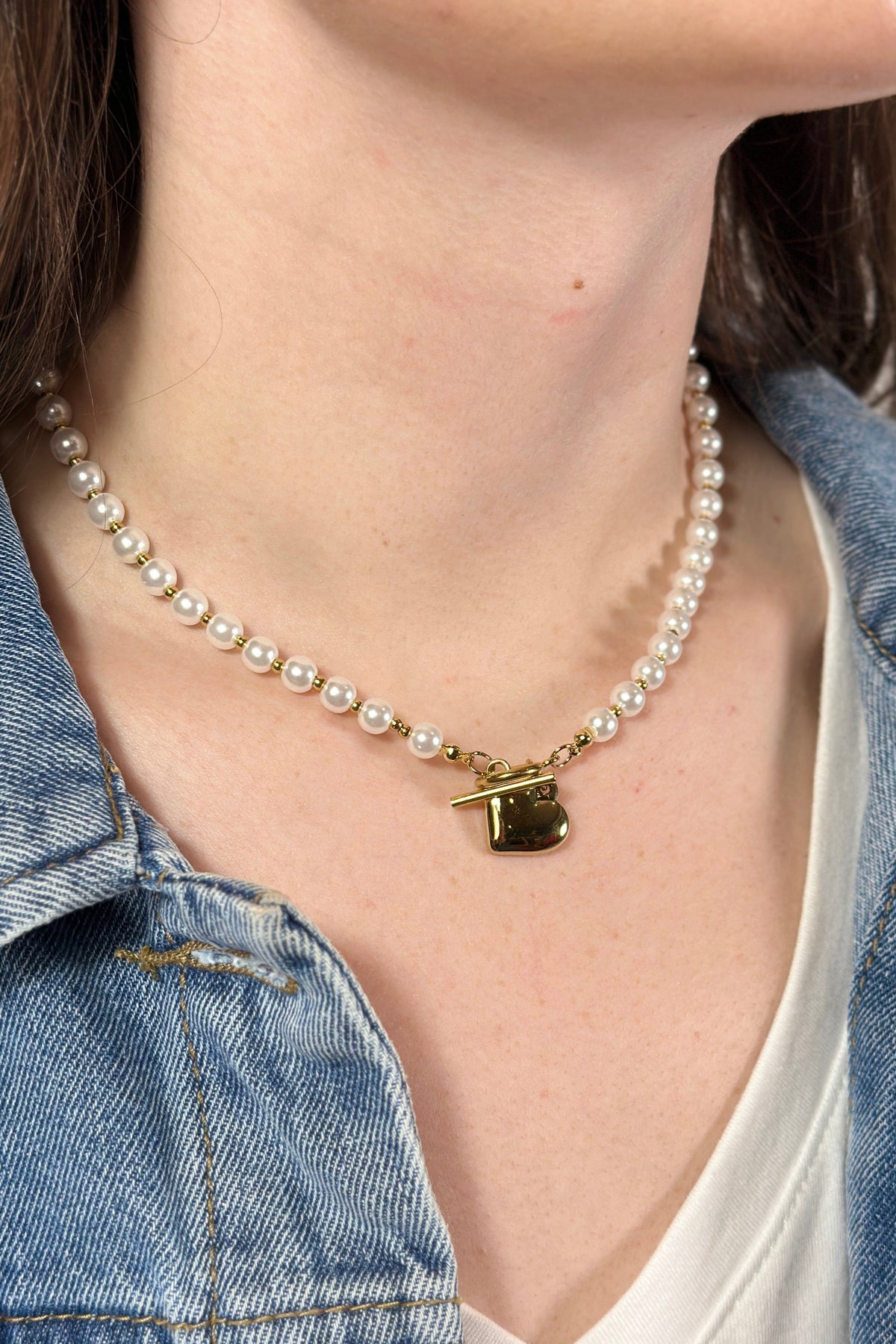 Model is wear a short pearl necklace with gold heart charm. 